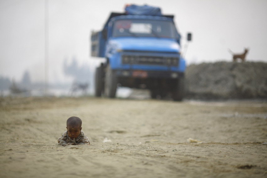 2012��3��18�գ�һ����ͯ������ӺӰ�������һ����·����ˣ��REUTERS/Staff
