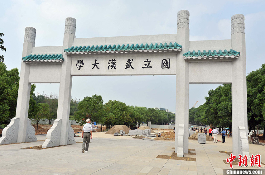 9月9日,武汉大学校门前的新牌坊前引得不少市民和师生在新牌坊前合影留念。去年10月9日,位于武昌八一路的武汉大学校门牌坊,在一声轰鸣声中化为尘埃。如今这座耗资近百万的新牌坊重回市民视线,和老牌坊相比,新牌坊按原貌重建,比原来退后10米放大1.2倍。中新社发 张畅 摄
