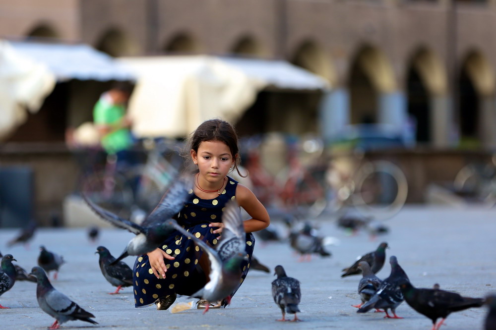 7月28日，在意大利帕多瓦，一名小女孩在聖安東尼教堂外的廣場上與鴿子玩耍。