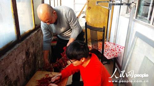王濤幫助父親剪碎自家晾晒的紅辣椒（紀宇攝）