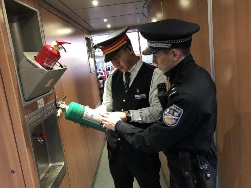 列車長鄭敏和乘警長崔江帆對列車上的滅火器進行檢查，查看滅火器的有效期和作用是否良好。