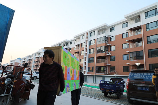 山東省濱州高新區小營街道辦事處的農民向新居內搬運家具。